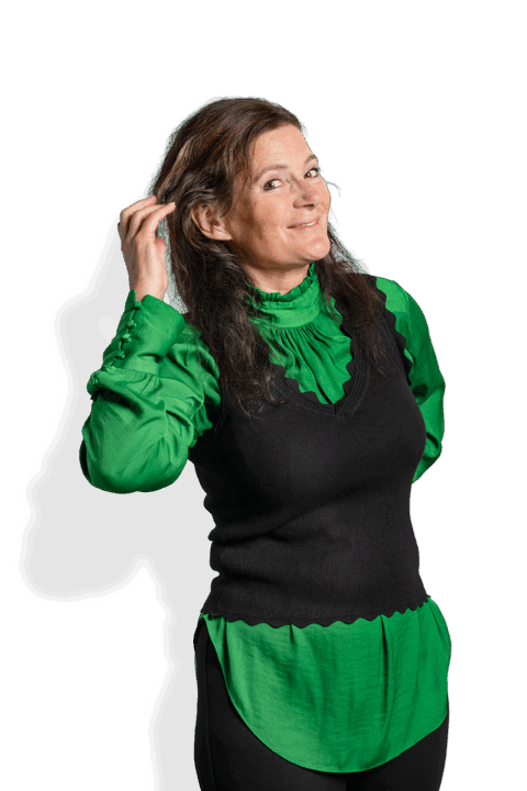 Koosje v. Frankenhuysen, eine Frau mit langen braunen Haaren, die eine hellgrüne Bluse und eine schwarze ärmellose Weste trägt, lächelt, während sie ihr Haar vor einem schlichten weißen Hintergrund berührt.