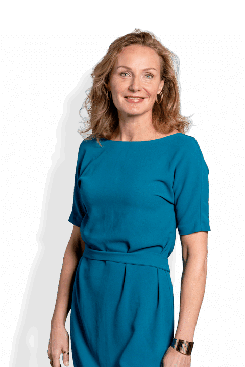 Eva van Rijn, een vrouw met blond golvend haar, staat glimlachend voor de camera in een groenblauwe jurk. Ze heeft hoepeloorbellen en een armband om haar rechterpols, met haar linkerarm ontspannen langs haar zij op een witte achtergrond.
