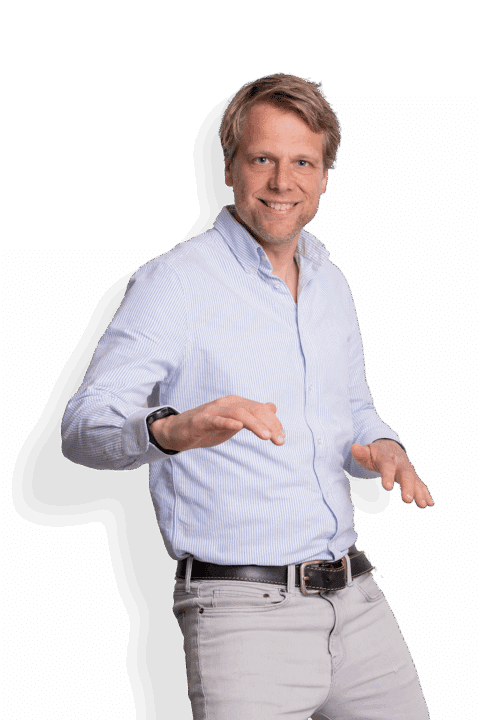 Ein lächelnder Mann mit blondem Haar, der Harro Yestra ähnelt, ein hellblau gestreiftes Hemd und hellgraue Hosen trägt und mit leicht erhobenen Armen posiert, als würde er tanzen oder gestikulieren, vor einem schlichten weißen Hintergrund.