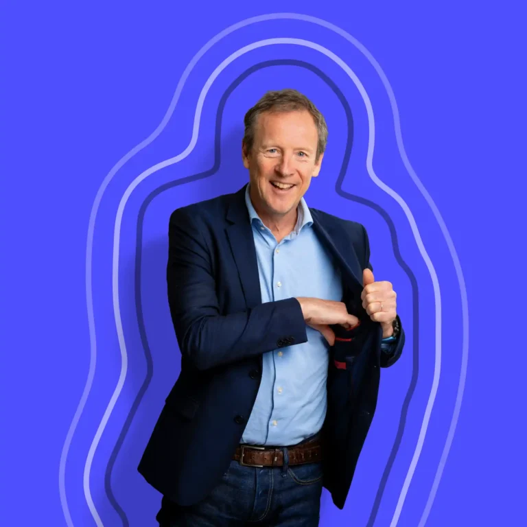A smiling man in a blue blazer and jeans stands against a vibrant blue background with wavy outlined shapes, holding his jacket open with one hand and giving a thumbs up with the other. A smiling man in a blue blazer and jeans stands against a vibrant blue background with wavy outlined shapes, holding his jacket open with one hand and giving a thumbs up with the other.